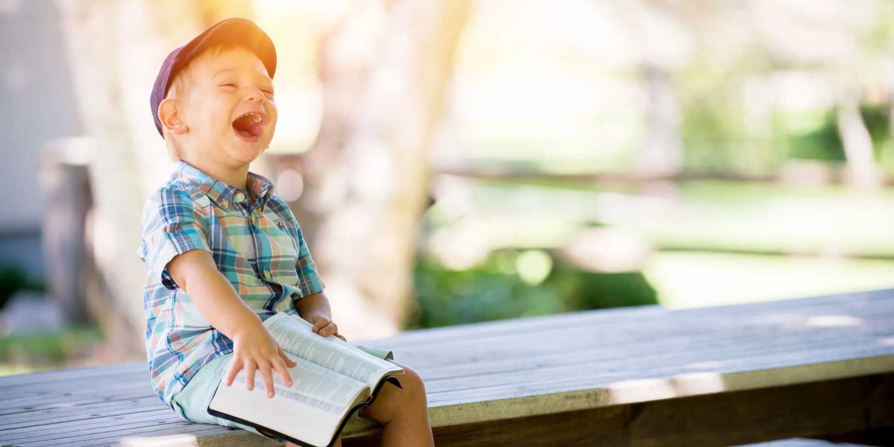young boy sitting on a bench with a book