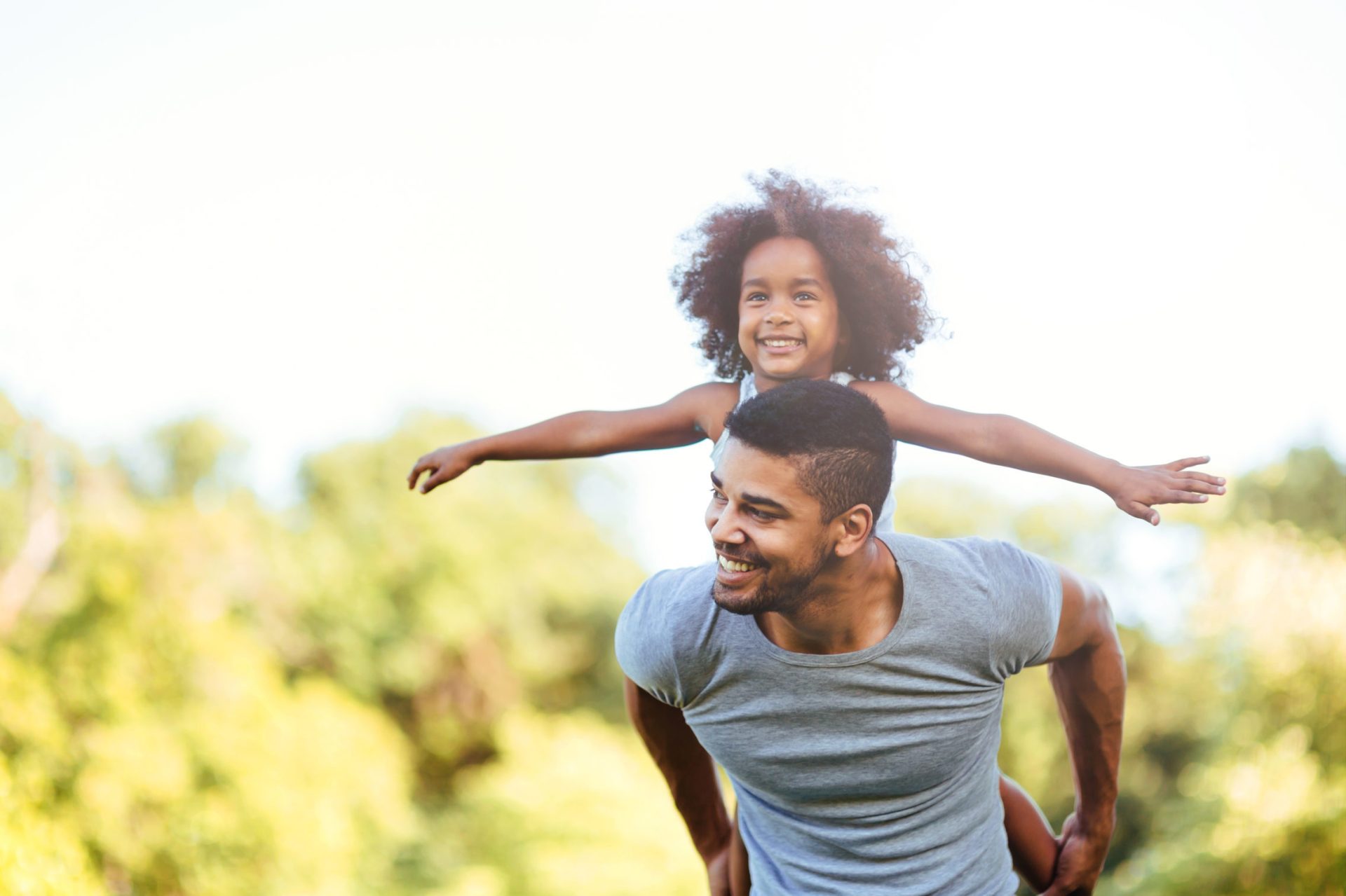 Portrait of young father carrying his daughter on his back