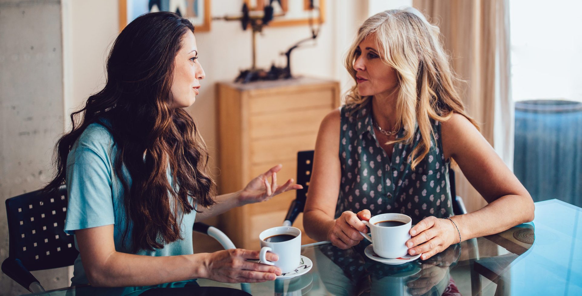 Senior mother and daughter drinking coffee together at home