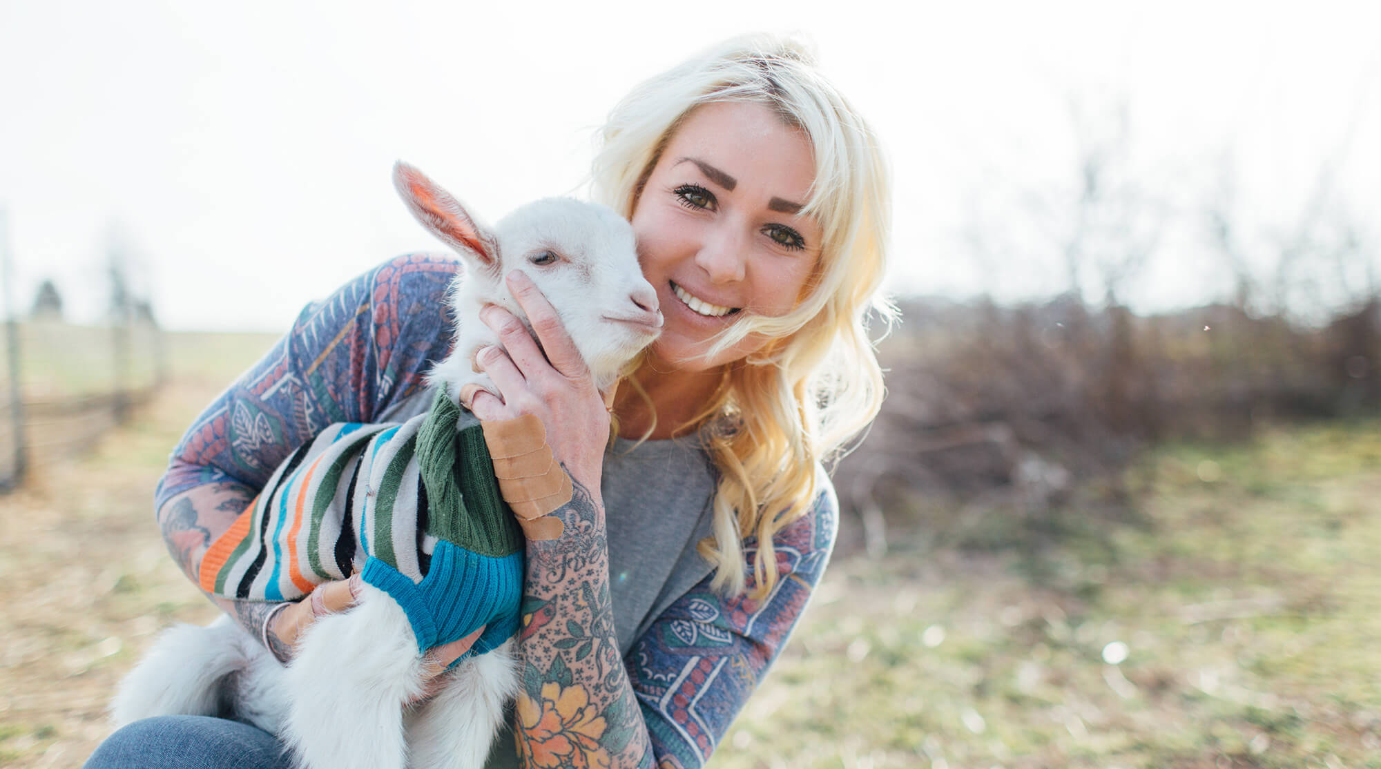 Woman smiling and holding a baby goat
