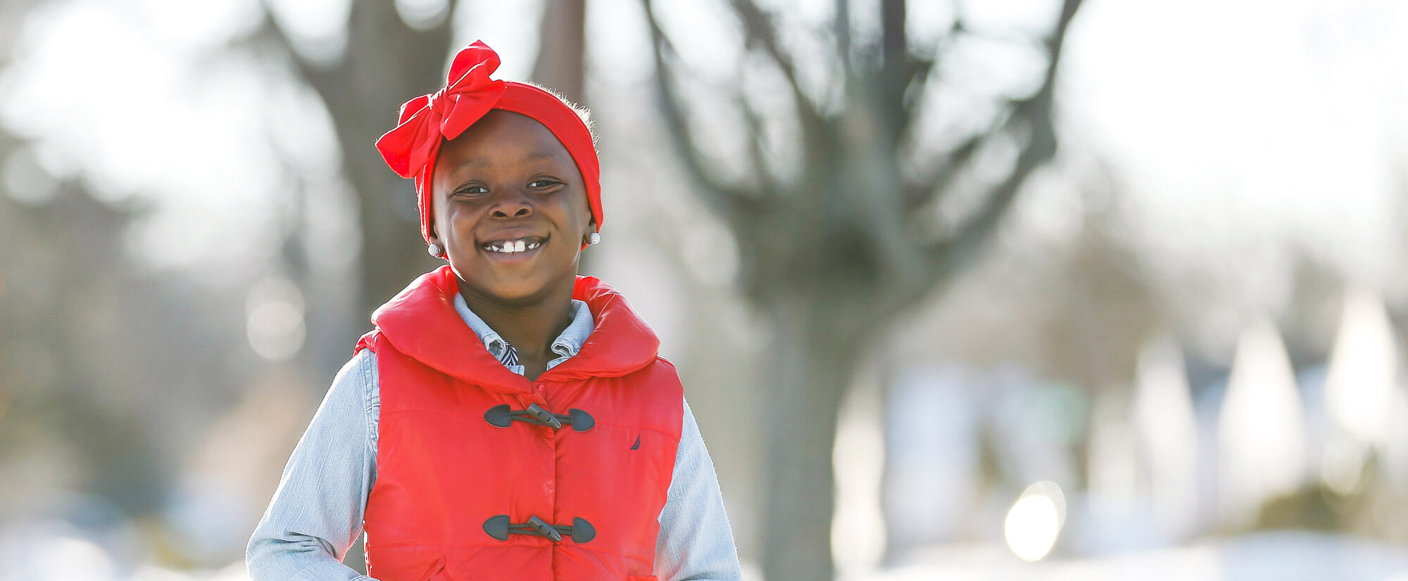Little girl in a red vest smiling