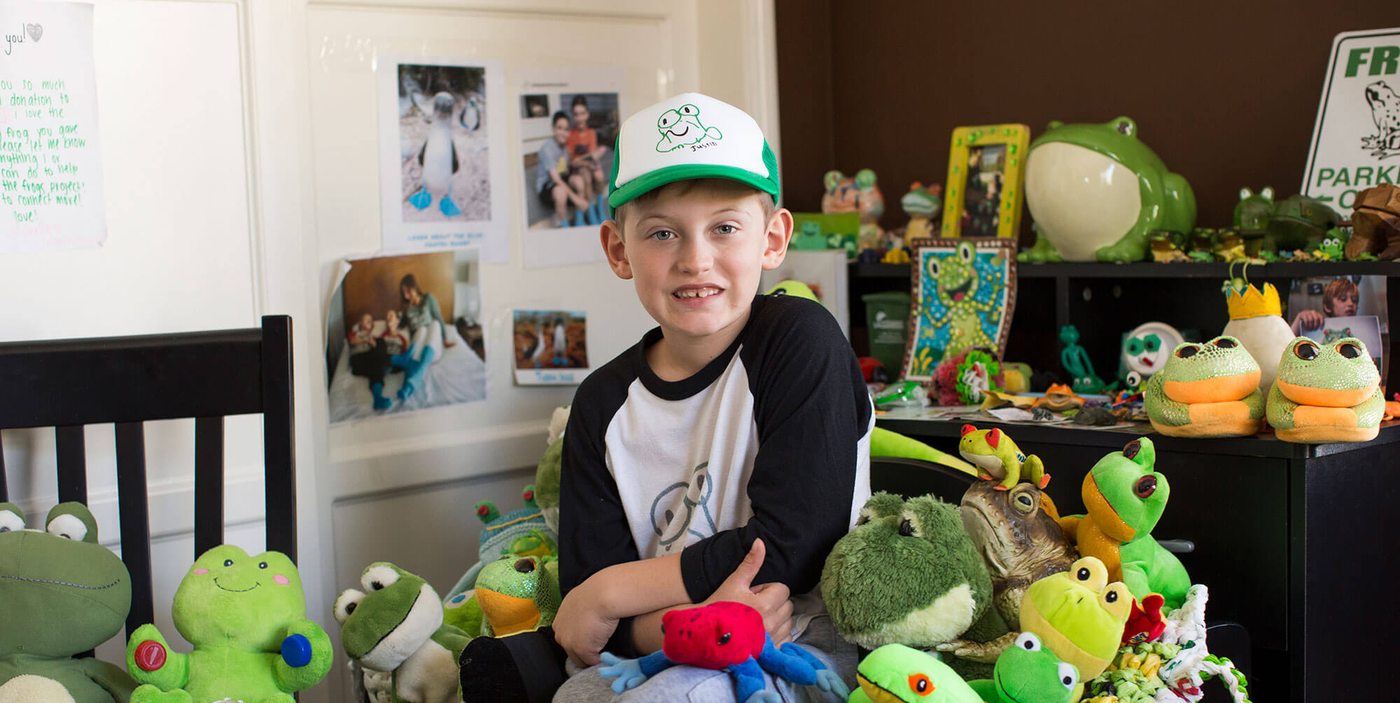 Image of a little boy sitting with stuffed animal frogs