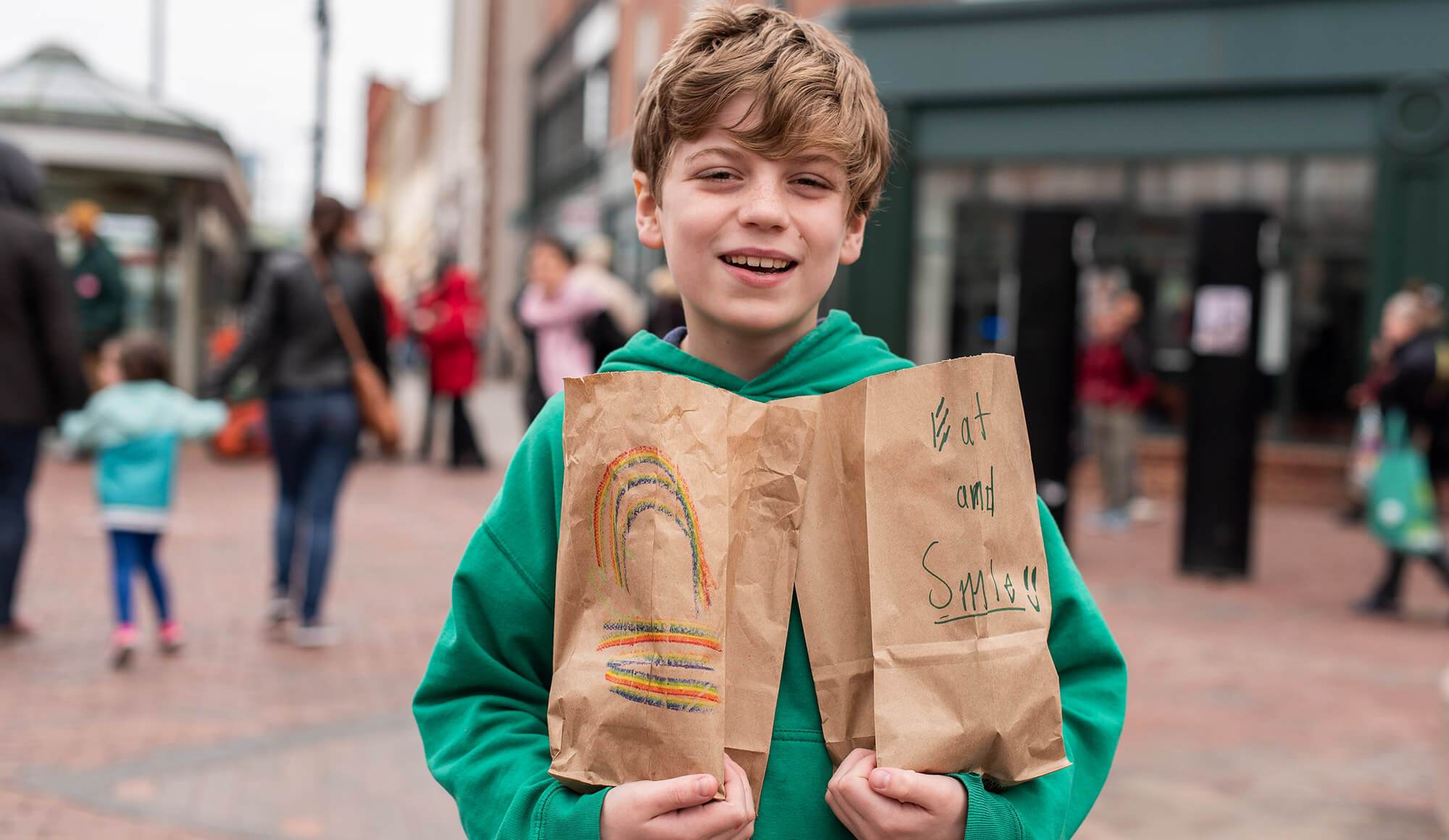 Boy smiling and holding two paper bags