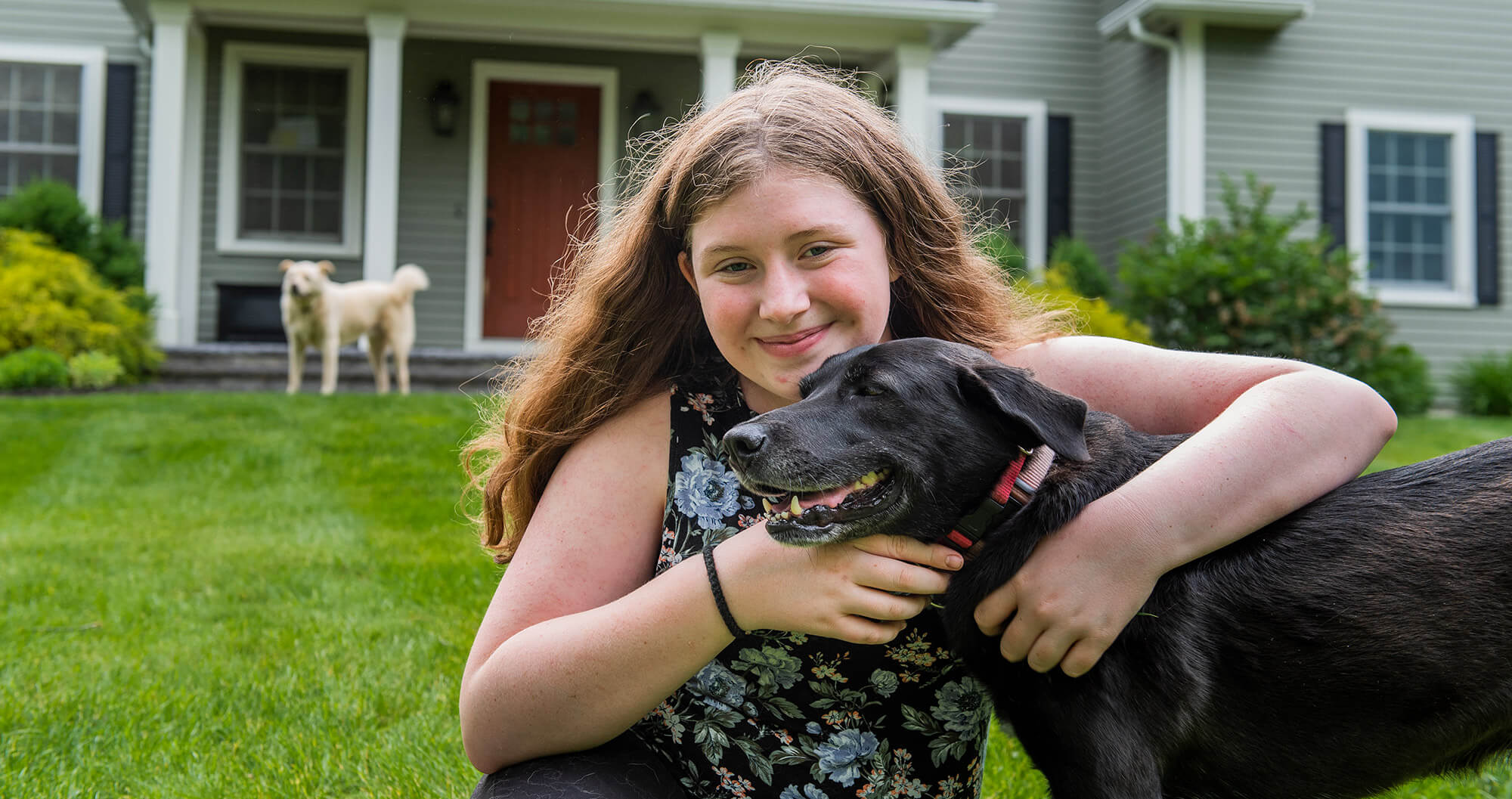 Girl smiling and holding a black dog
