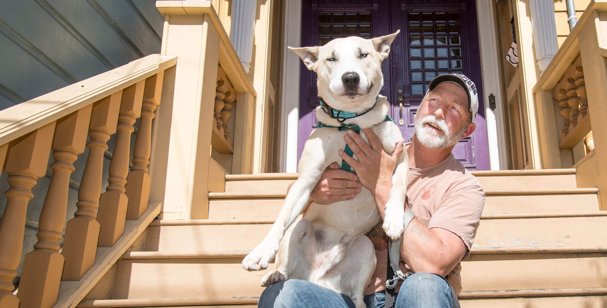 Man sitting on steps holding white dog