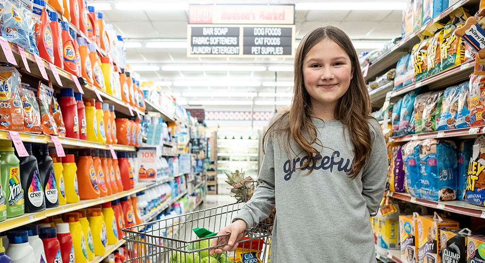 Girl standing in a store aisle with grocery cart