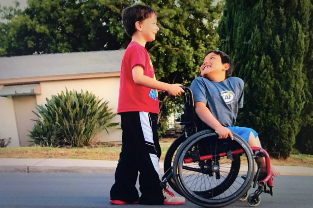 Boy pushing a second boy in a wheelchair