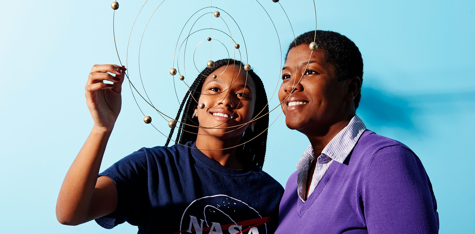 Young girl and woman looking at a mini solar system model