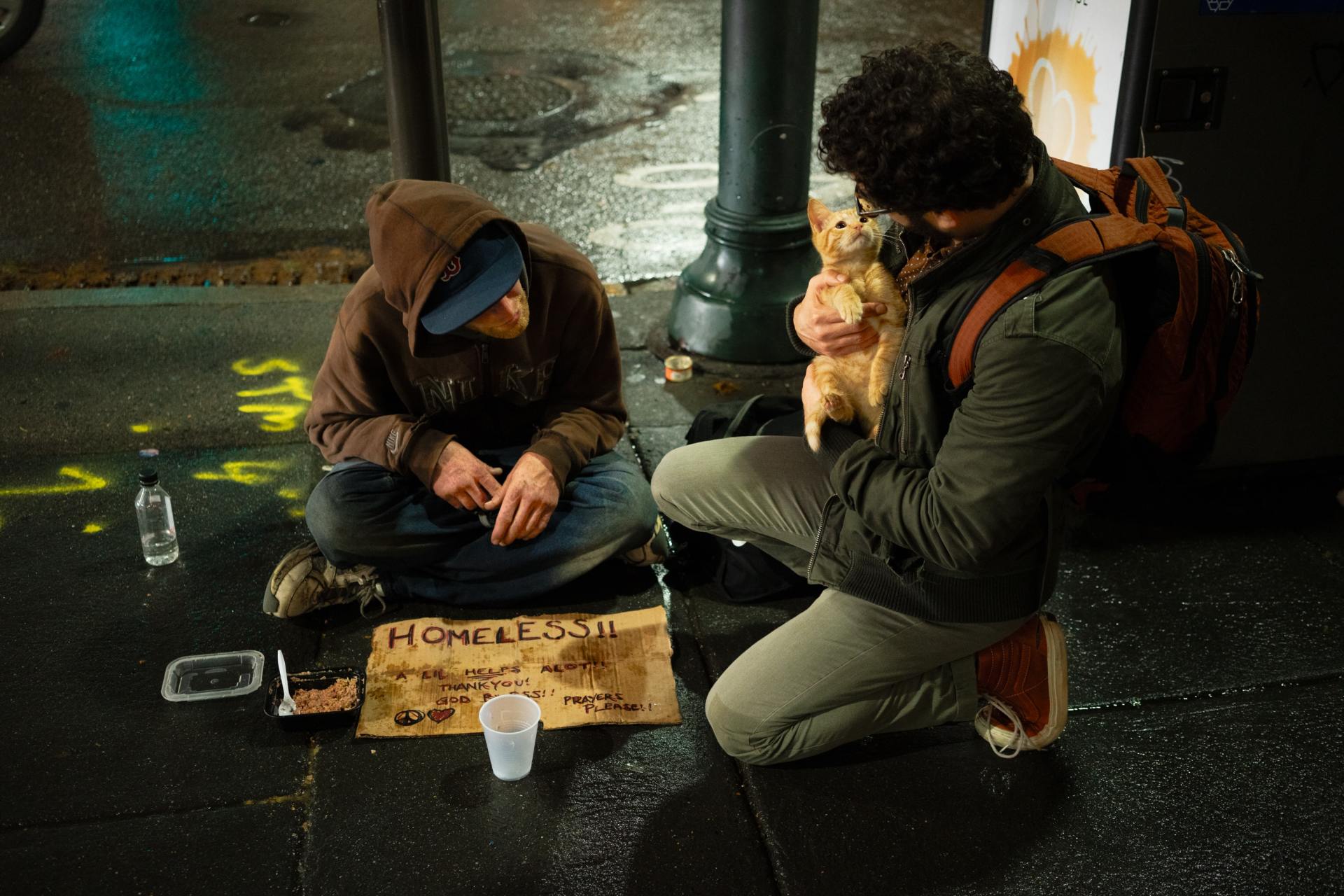 An individual with a cat talking to a homeless person