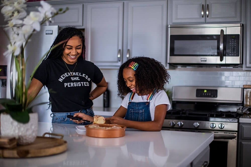 Young girl and young woman standing in a kitchen