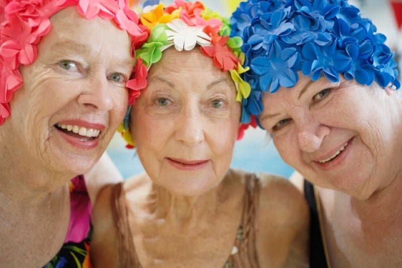 Three older people wearing colorful floral headbands