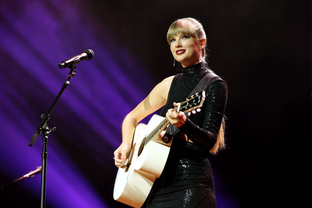 taylor swift smiling and holding a guitar