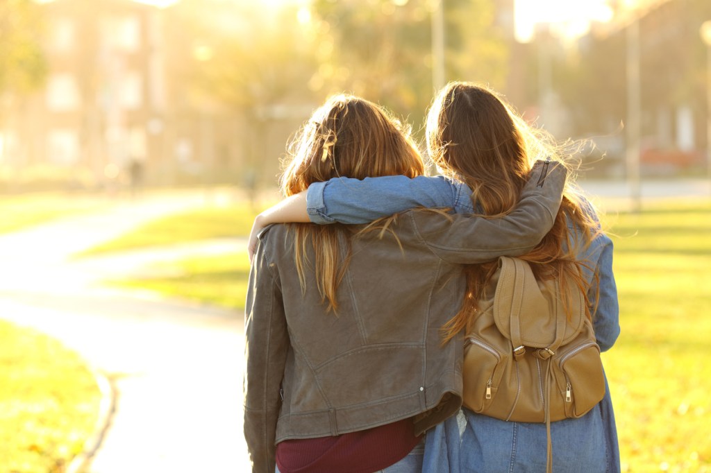 two friends walking at sunset in a park