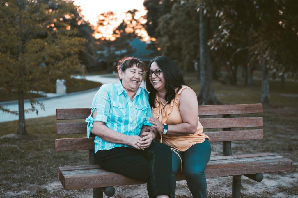Two people smiling and sitting together on a bench