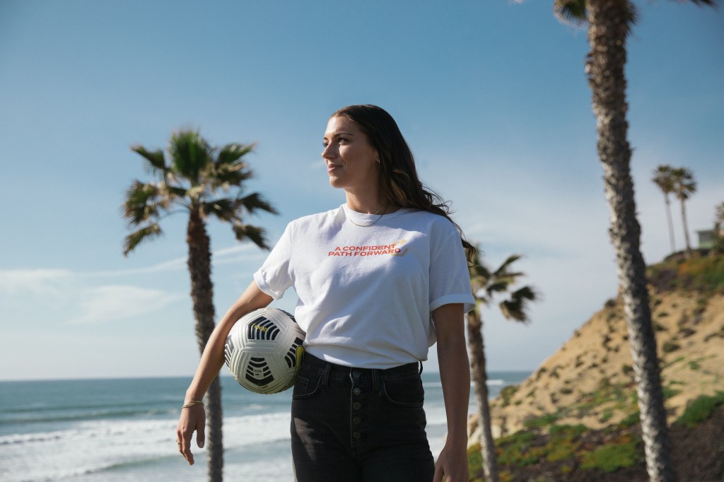 Alex Morgan holding a soccer ball outside