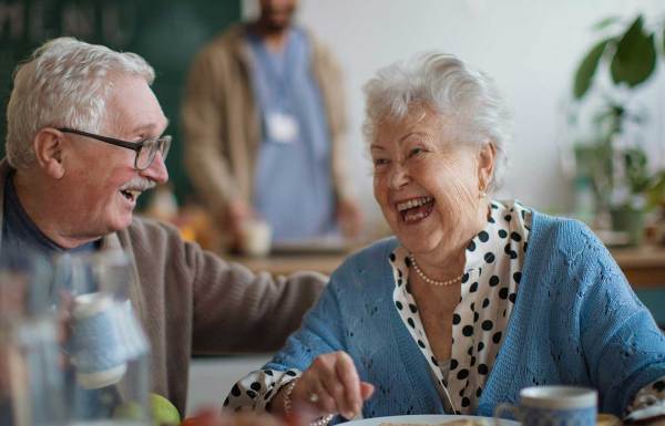 An elderly couple laughing together and sharing a meal