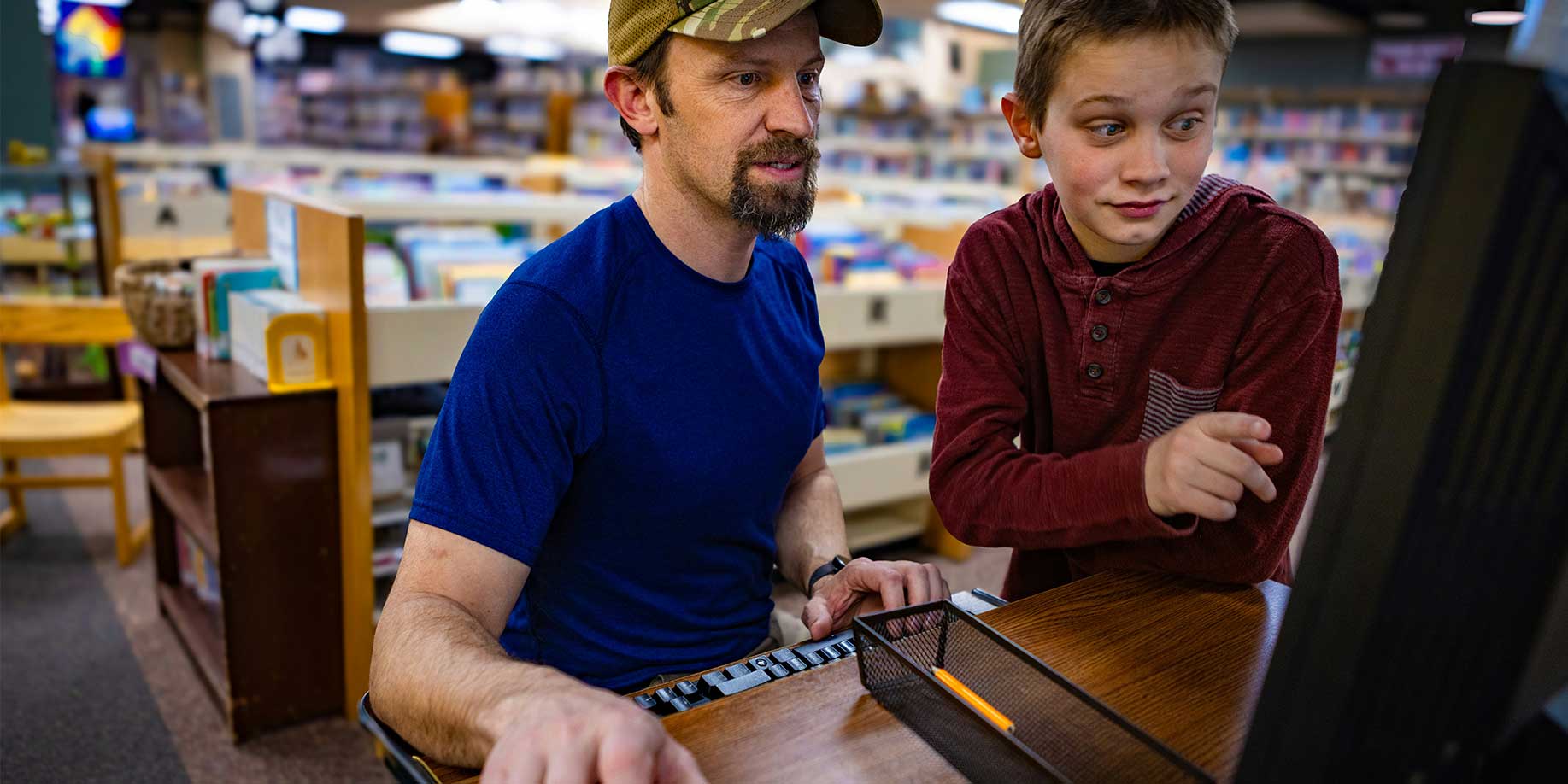 a father and son using a computer at the library