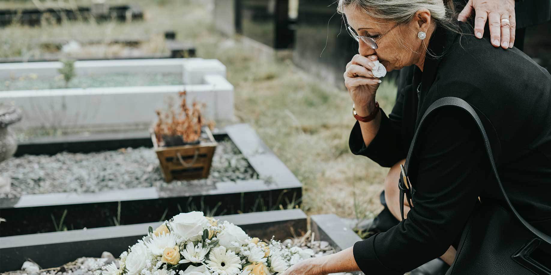 A woman laying flowers on a grave