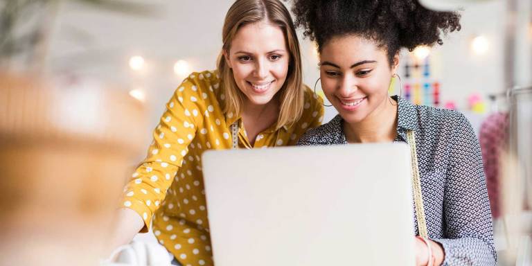 Two friends using a laptop to create a fundraiser