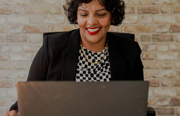 Woman smiling while working on a laptop