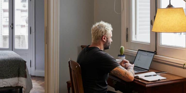 Man sitting at a laptop with an open notebook