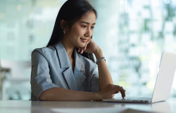 A woman smiling while using a laptop