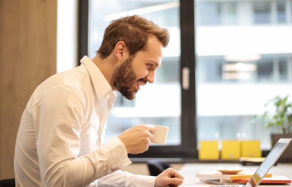 Ein Mann, der Kaffee trinkt und an seinem Laptop arbeitet