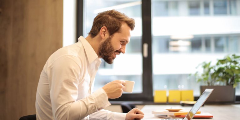 Ein Mann, der Kaffee trinkt und an seinem Laptop arbeitet