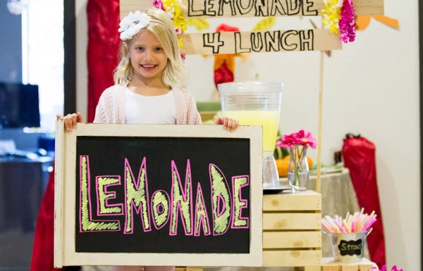 Young girl holding up a sign for her lemonade stand