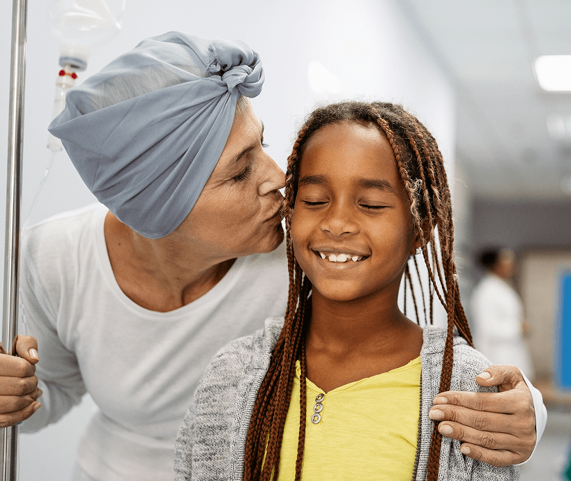 A cancer patient giving her daughter a kiss on the cheek