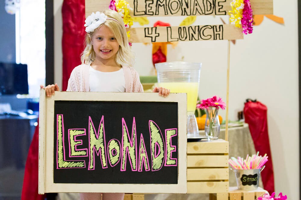 Young girl holding up a sign for her lemonade stand