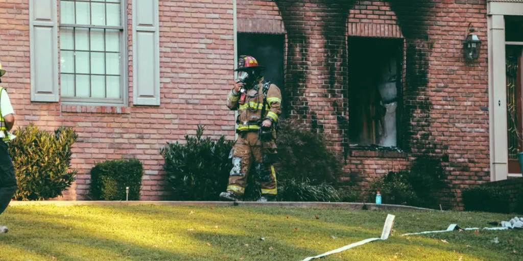Firefighter walking out of a house