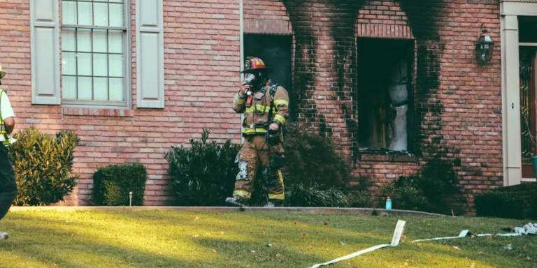 Firefighter walking out of a house