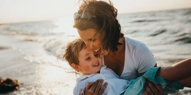 A mother playing on the beach with her son