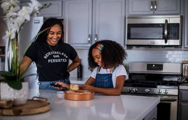 Young girl and young woman standing in a kitchen