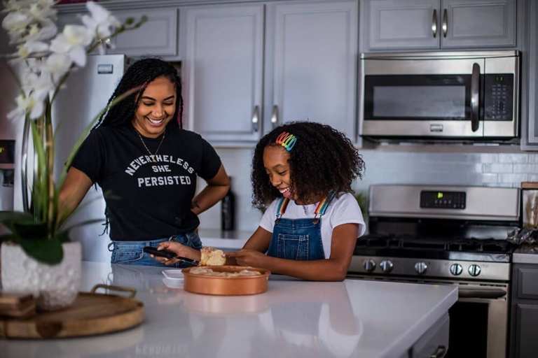 Young girl and young woman standing in a kitchen