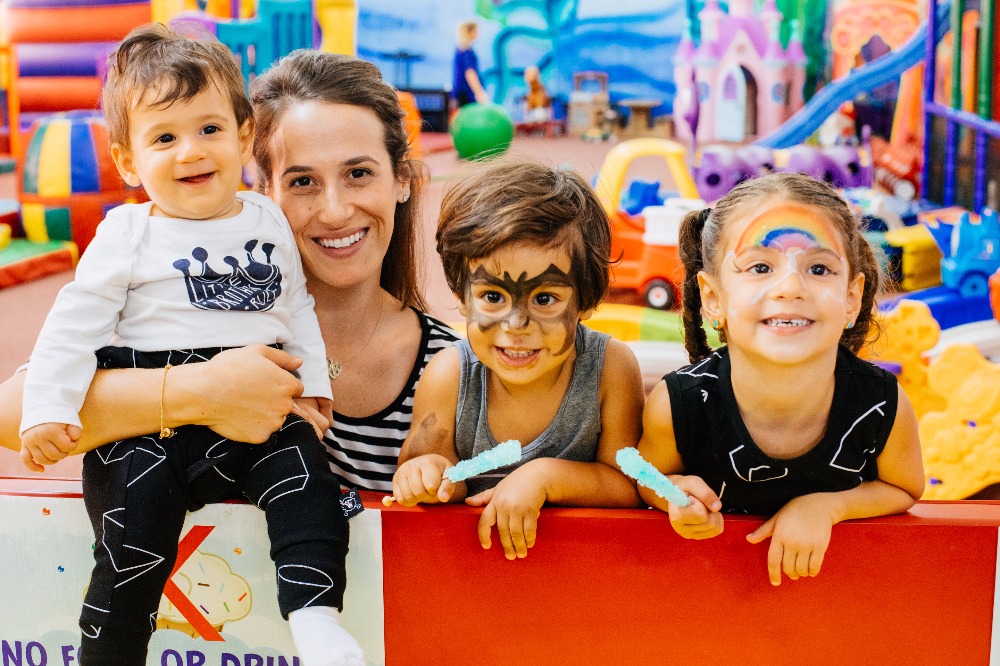 Mom and her three young kids with face painting