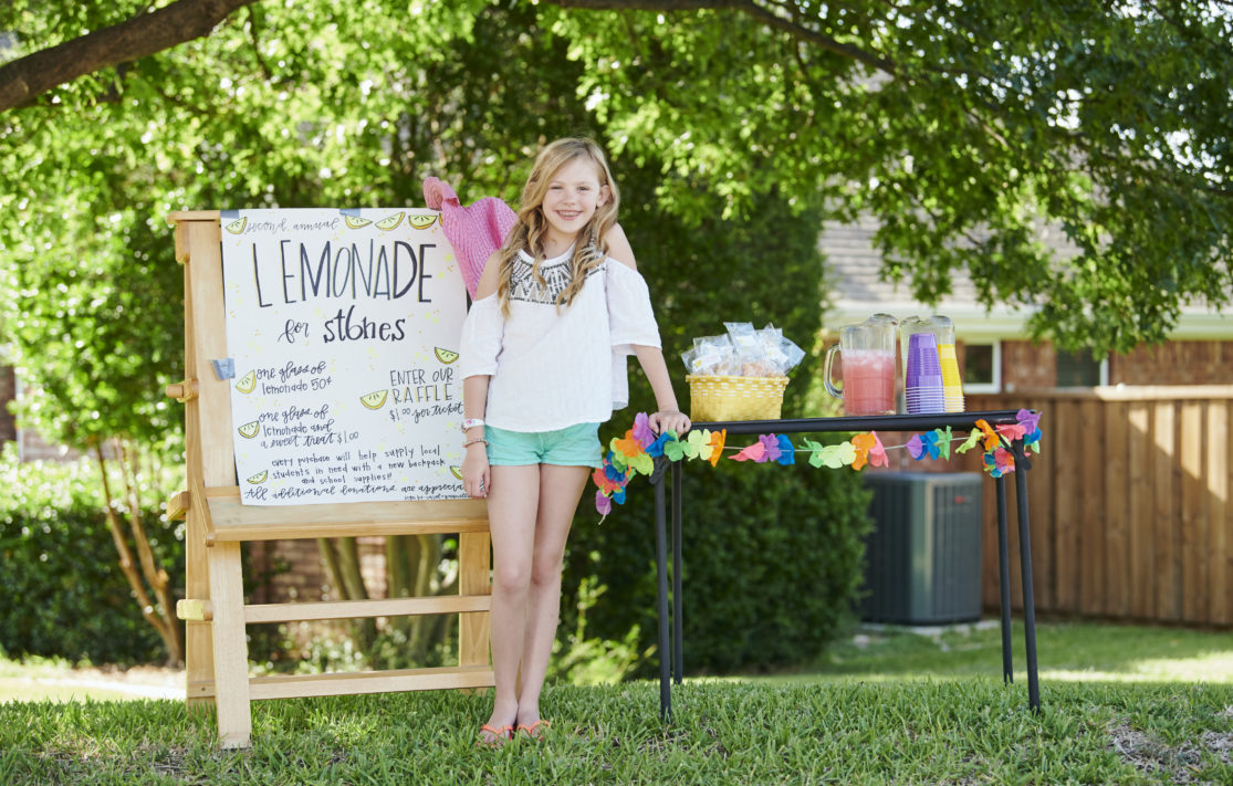 Young girl psoing in front of her lemonade stand for charity