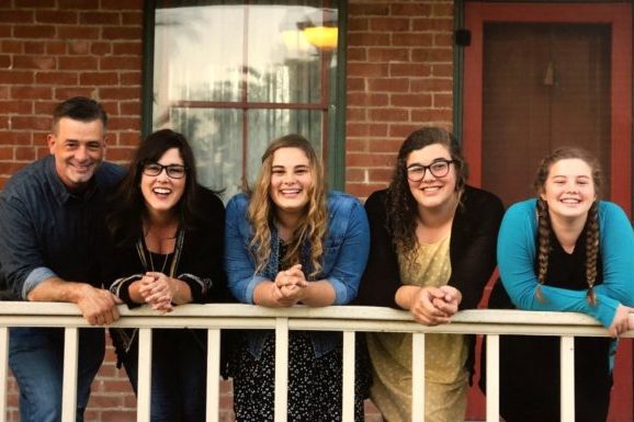 A family stood in a row leaning on a bannister