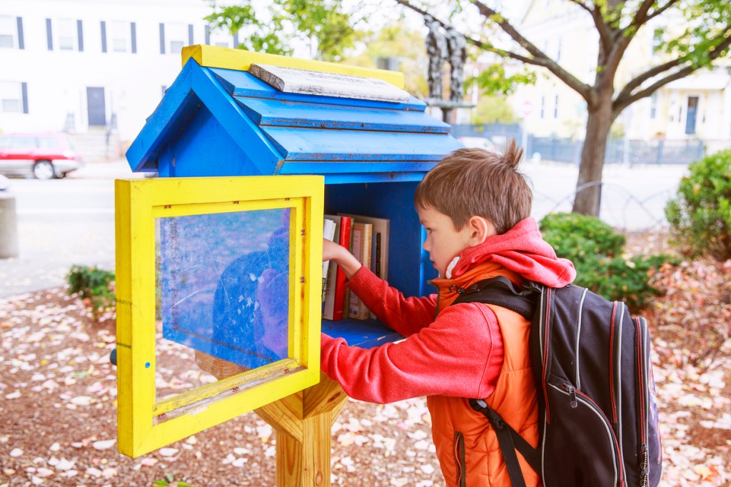 boy putting books in free little library