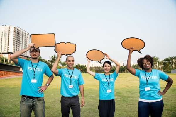 four people holding word bubbles