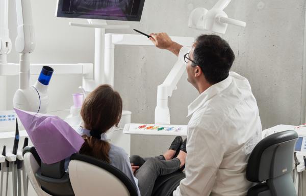 Un dentista revisa las historias clínicas con un paciente