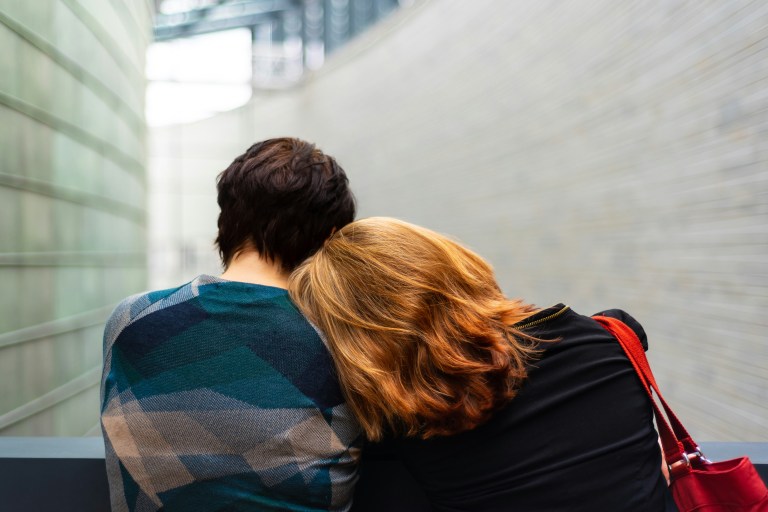 una persona que apoya la cabeza en los hombros de otra