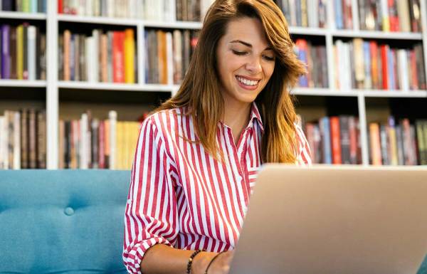 une femme souriante qui organise une collecte de fonds sur un ordinateur portable