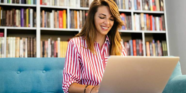 une femme souriante qui organise une collecte de fonds sur un ordinateur portable