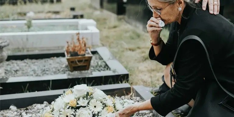 une femme en deuil devant une tombe