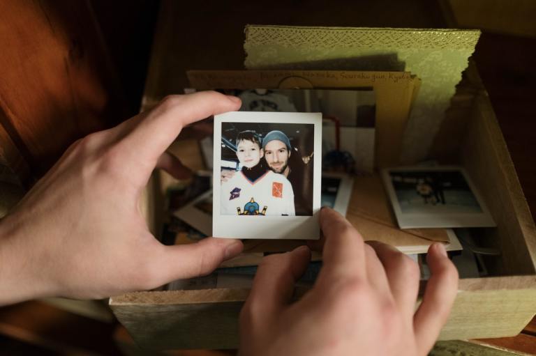 Mains tenant une petite photo de deux amies joue contre joue