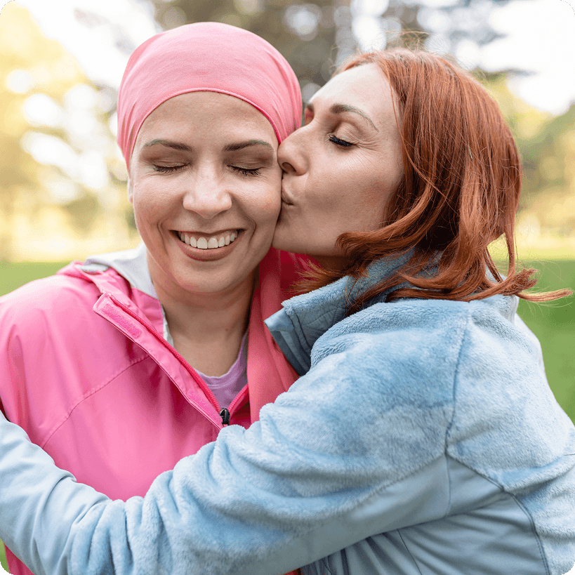 Une amie qui donne un baiser sur la joue à son amie atteinte d’un cancer du sein