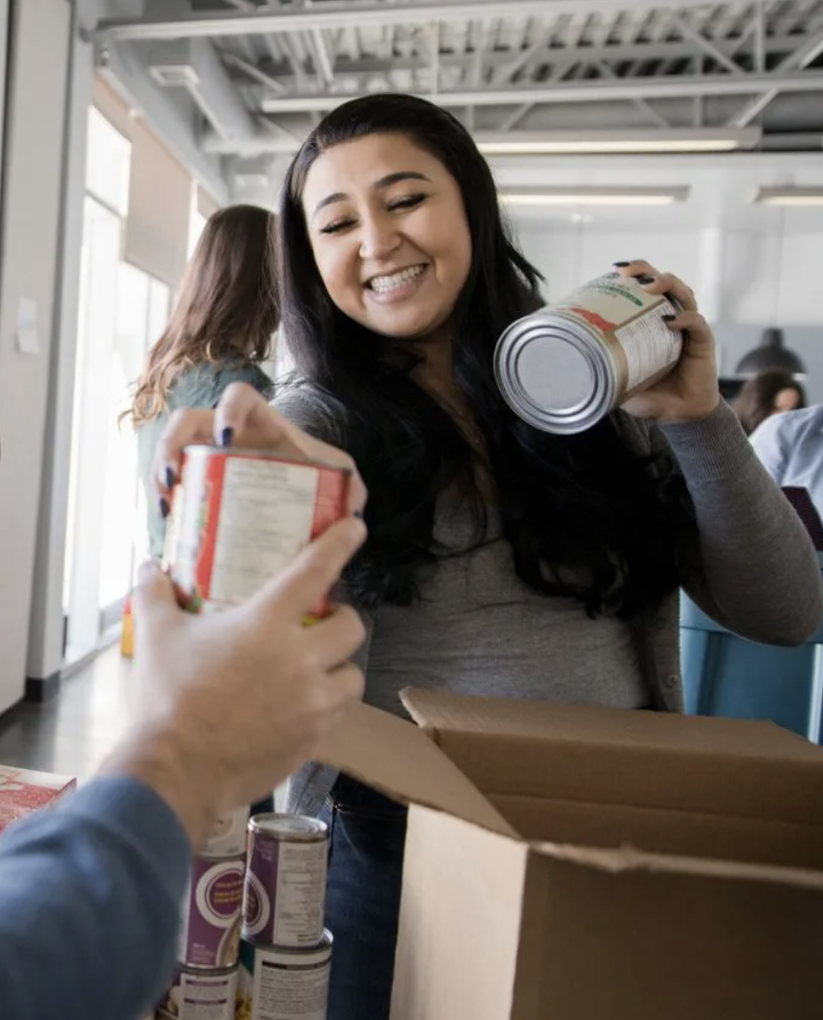 une bénévole souriante en train d'emballer des produits non périssables