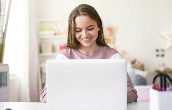 een glimlachende persoon achter een computer